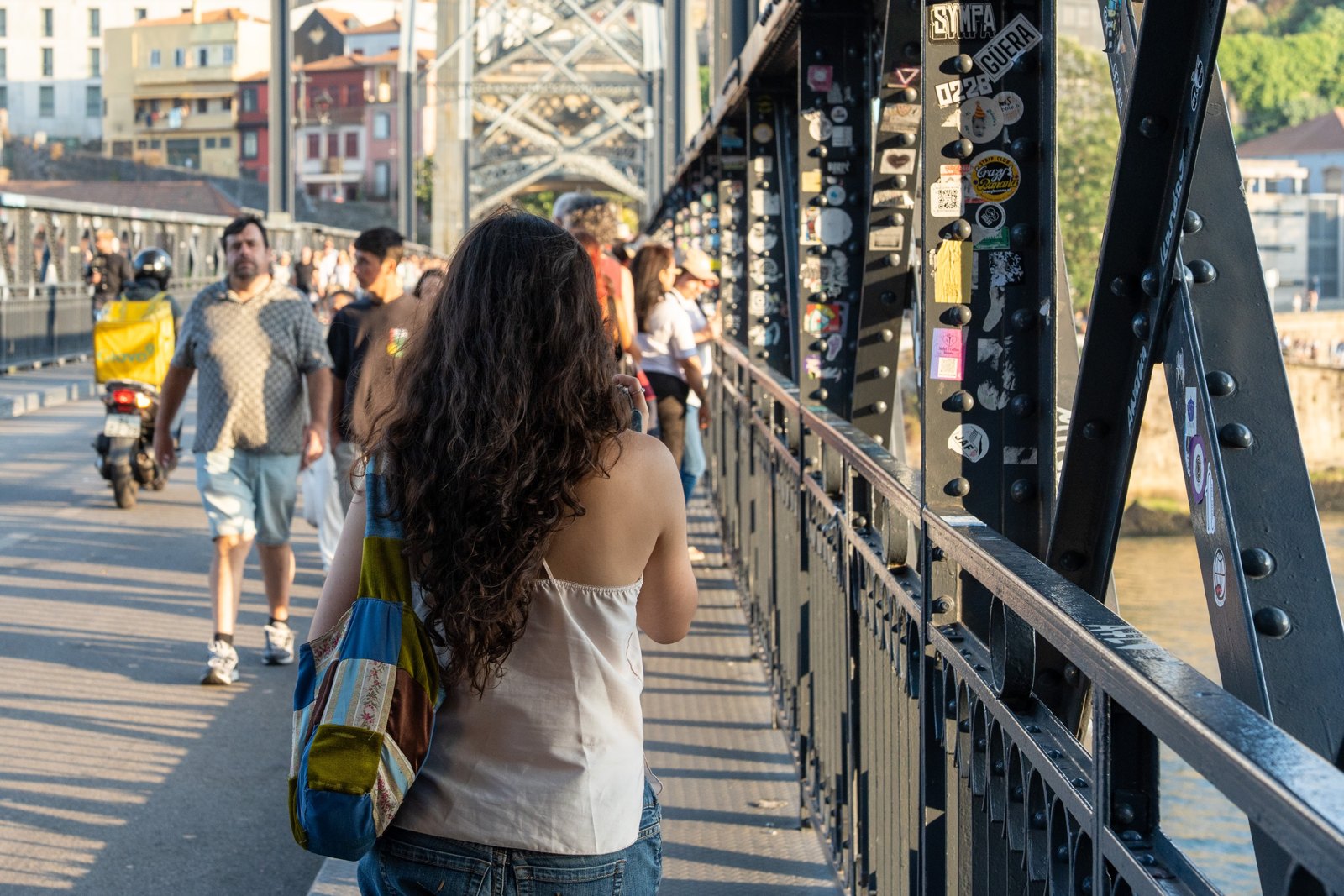 A pedestrian walks beside riveted beams covered in stickers.