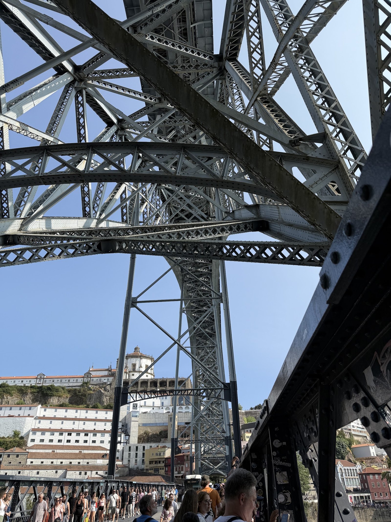 Looking up through intersecting metal arches and beams into a blue sky.
