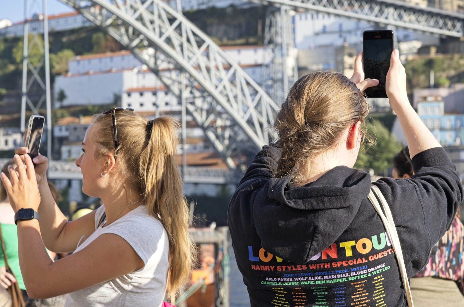 Two visitors raise their phones to photograph the bridge.