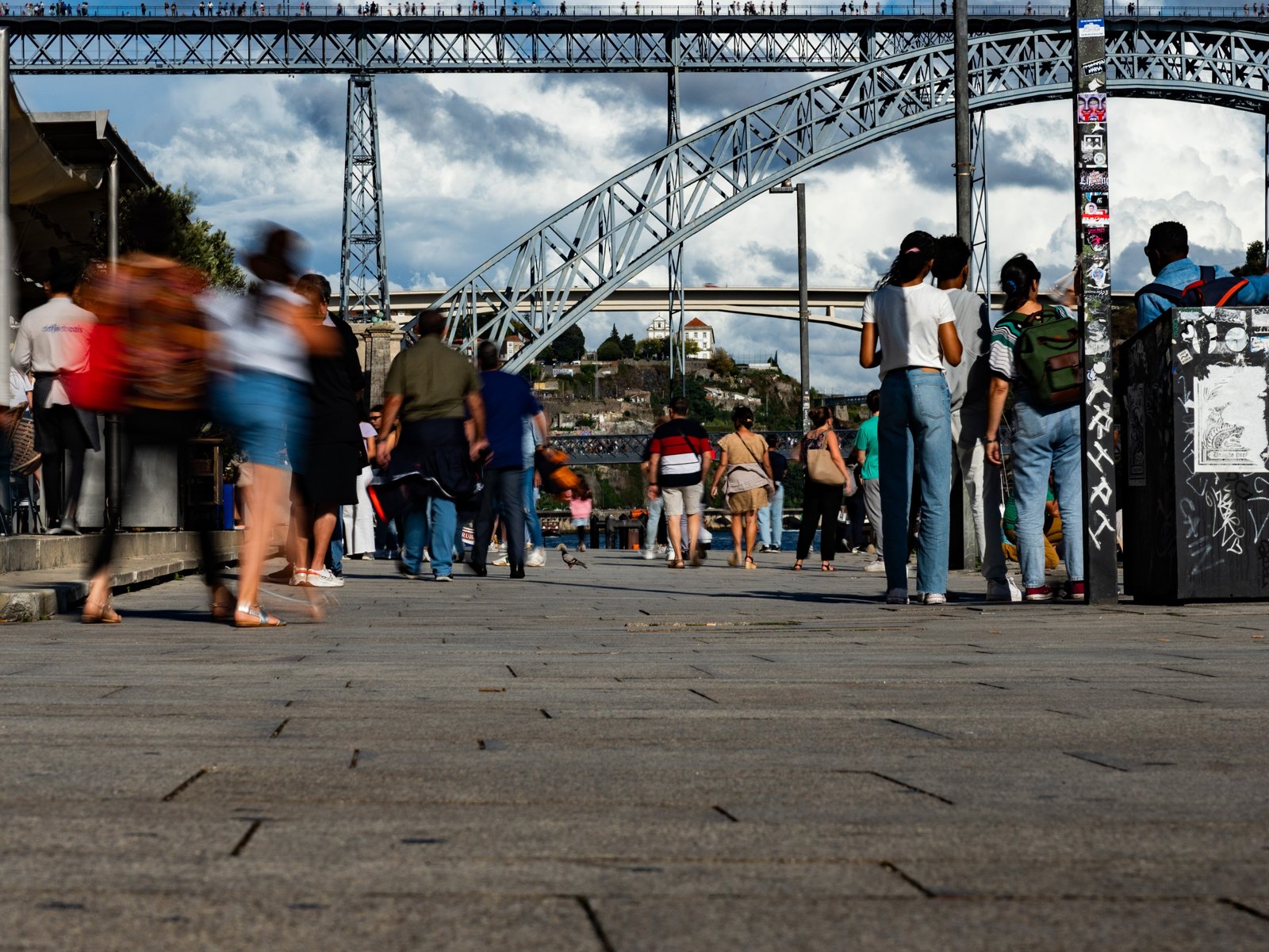 Moving and stationary figures on the quay beneath the bridge’s broad arch.