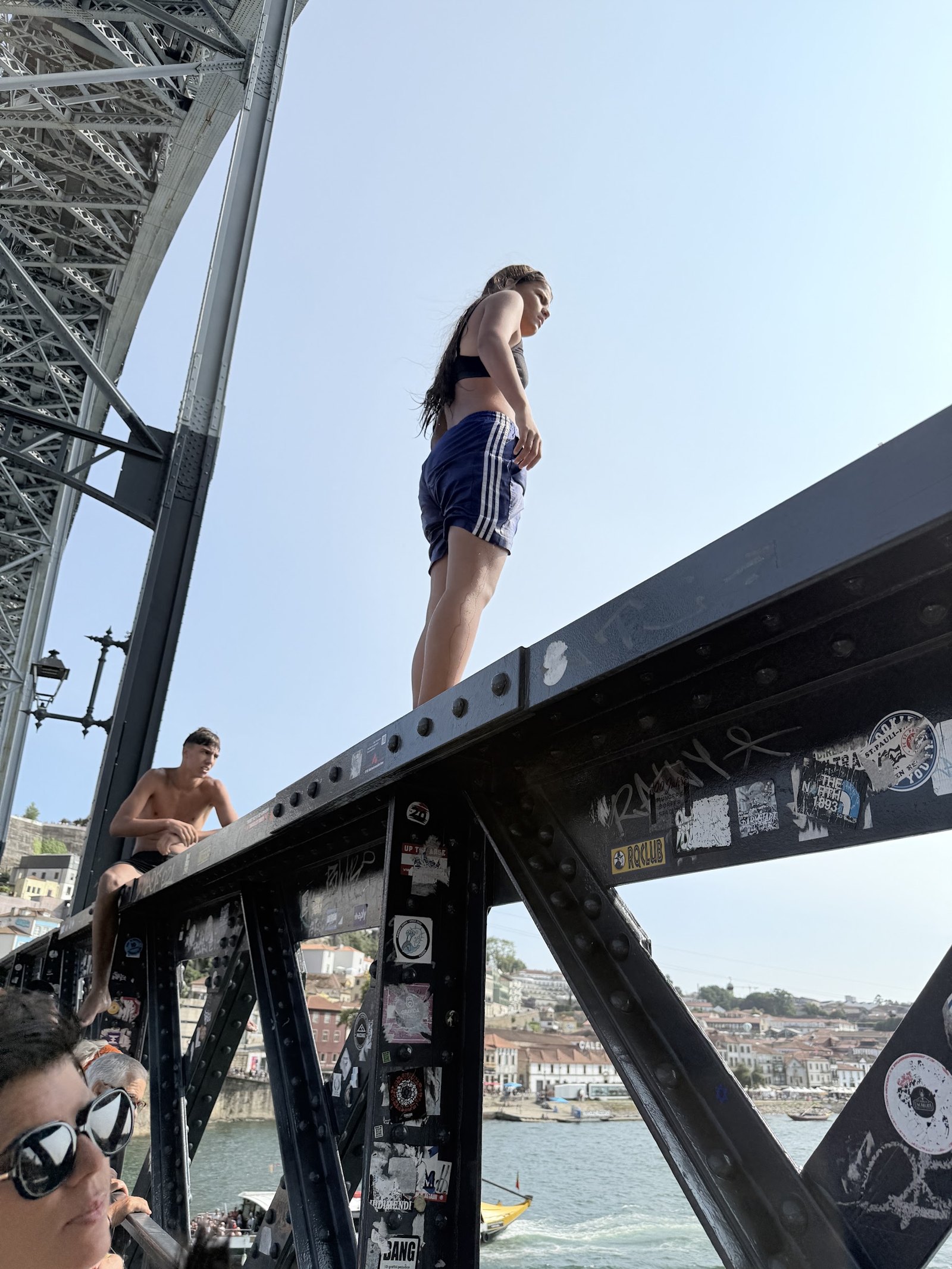 Two people perched on the bridge’s metal structure above the river.